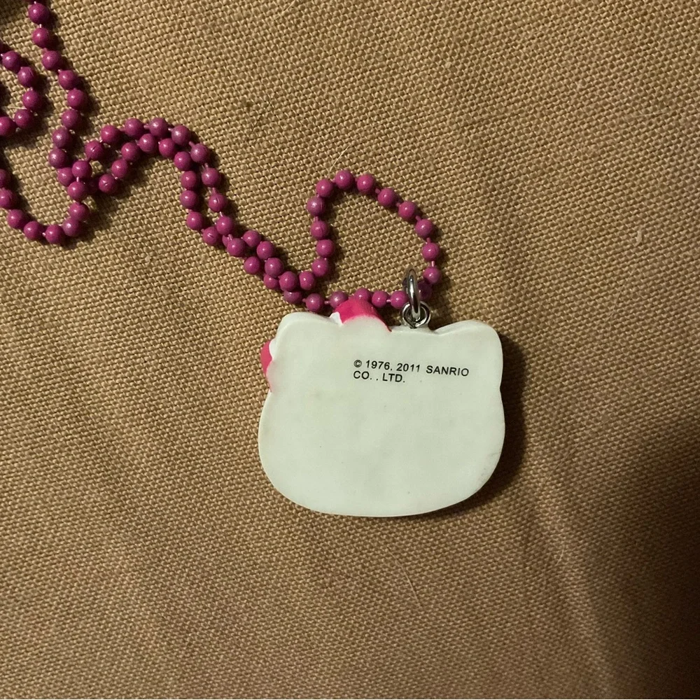 Hello Kitty :Kitty face slightly angled on a bight pink beaded necklace blue bow